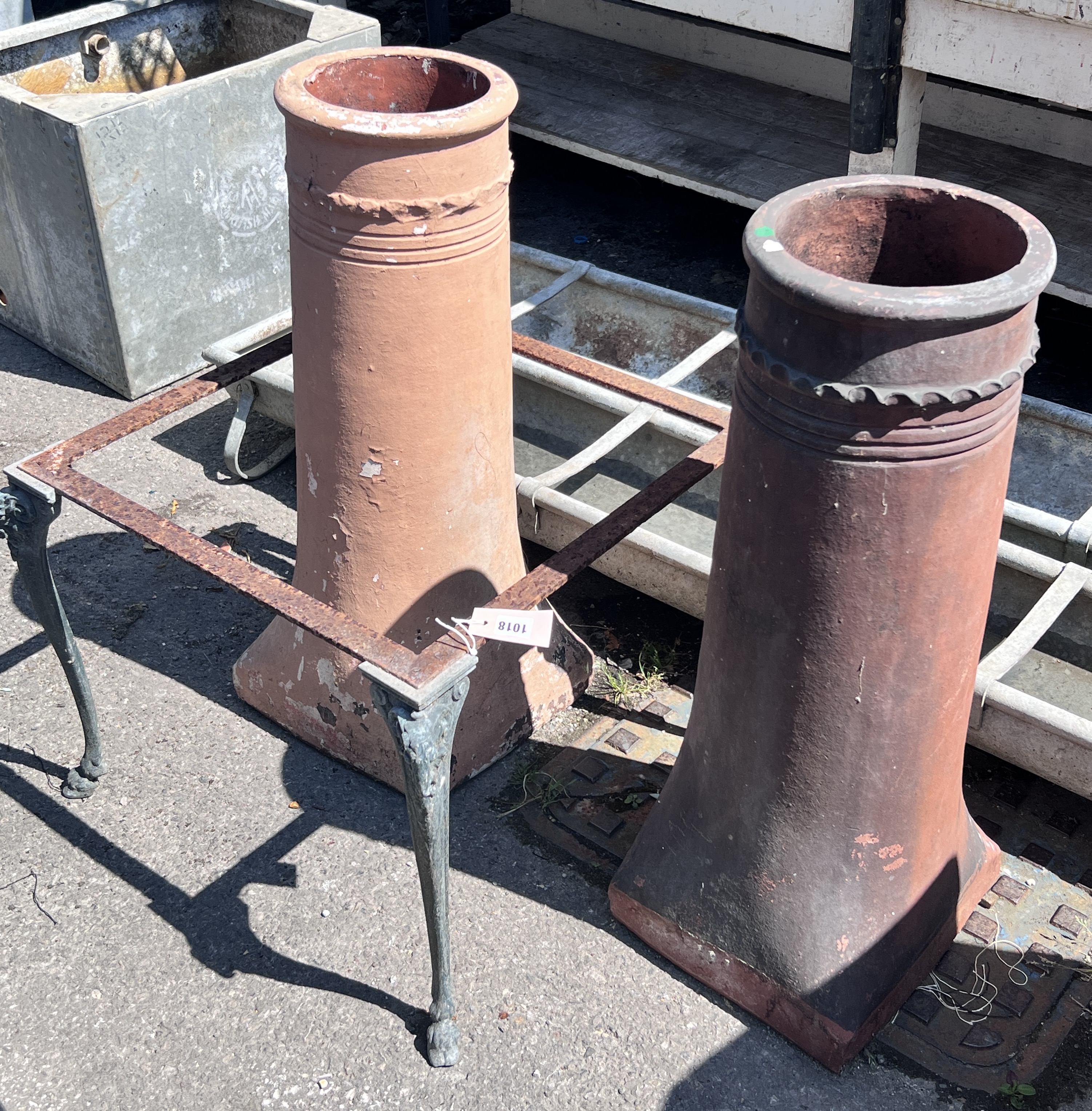 Two terracotta chimney pots, height 77cm, together with a square metal table frame